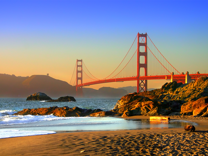 Sunset at Baker Beach with the ocean, rocks, mountains and the Bay Bridge