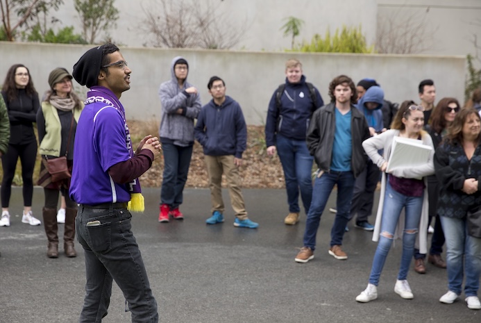 Gator tour guide in a purple shirt talking to several students and parents on a SFSU campus tour