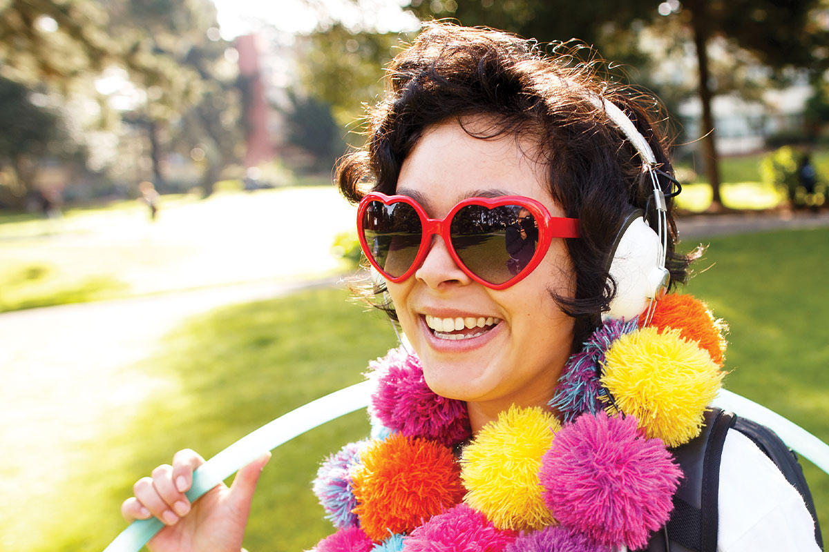 SF State student wearing heart glasses with pompoms and hula hoop
